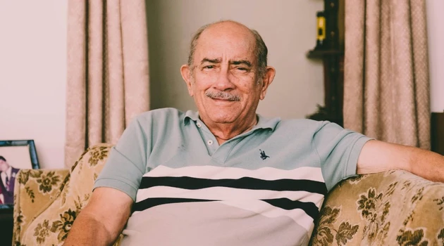 Man sitting on couch smiling at camera.