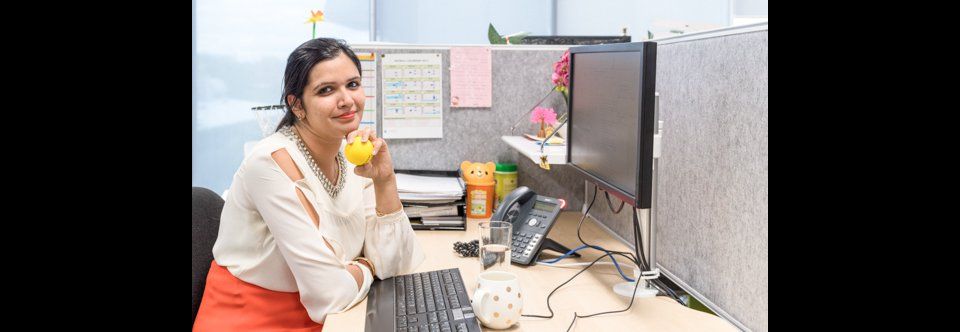 Woman holds stressball smiling at desk