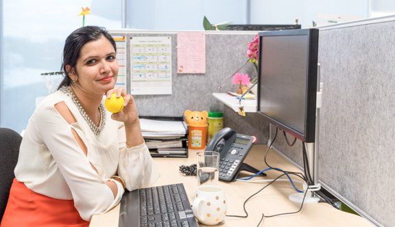 Woman holds stressball smiling at desk