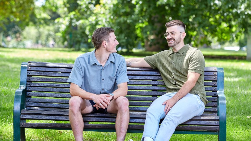 two men sitting on a park bench in conversation